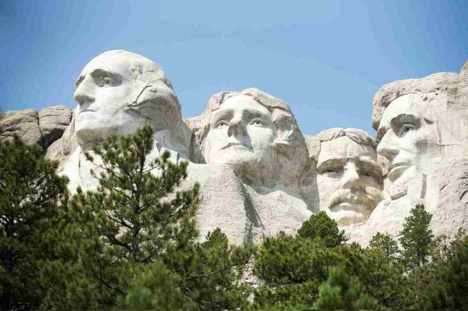 Nacionalinio paminklo „Mount Rushmore“ vaizdas žemu kampu prieš skaidrų dangų