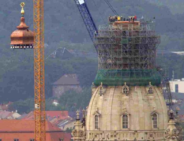 Kranas kelia vario kupolą ir auksinį kryžių į rekonstruotos Frauenkirche viršūnę Drezdene, Vokietijoje