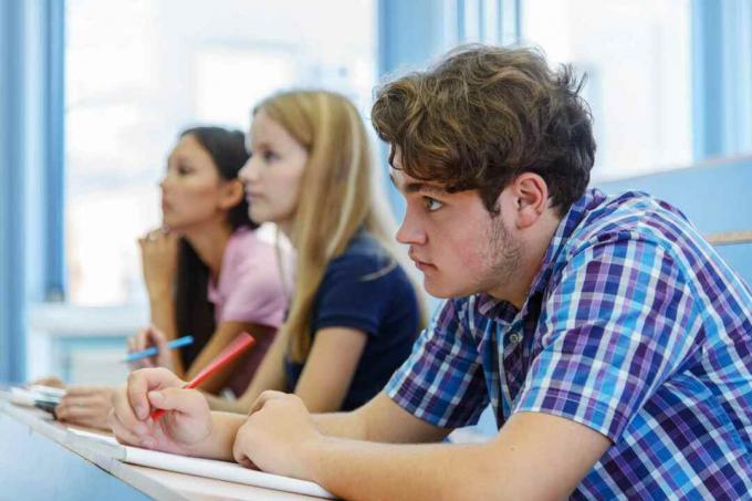 3 estetiantes atentos en un aula