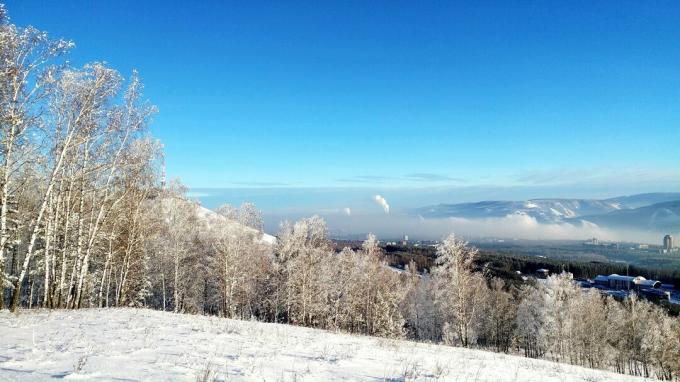 Vaizdingas sniego padengto peizažo vaizdas prieš mėlyną dangų