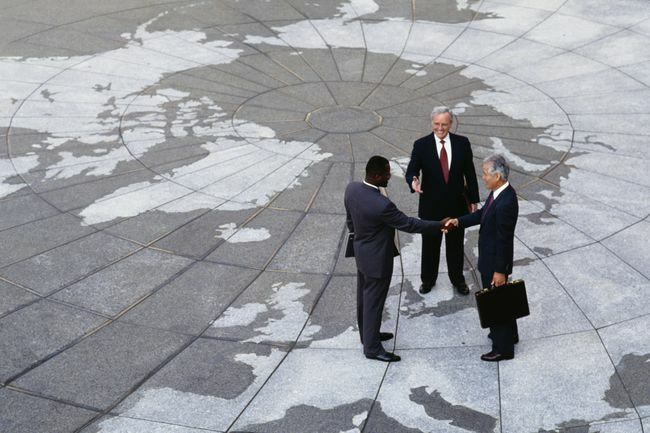  Ekonominis regionizmas: verslininkai skėsčioja rankomis Žemės rutulio žemėlapyje.